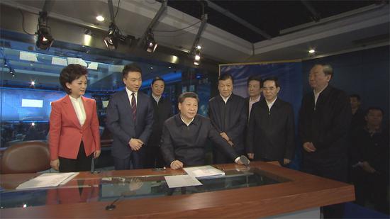 在中央電視臺《新聞聯(lián)播》演播室、導(dǎo)播室,習(xí)近平向主持人和工作人員了解新聞制播流程,并親自切換按鈕體驗?zāi)M播出。