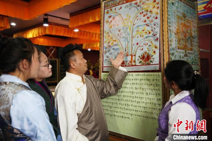 圖為普窮次仁(男)正在向?qū)W生講解“四部醫(yī)典”掛圖。(資料圖) 普窮次仁供圖