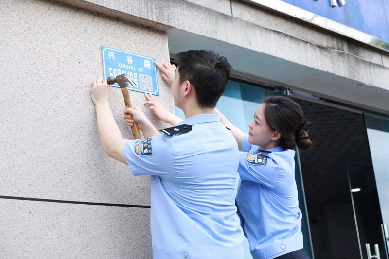 民警在興谷路裝訂二維碼門樓牌。重慶高新區(qū)公安分局供圖